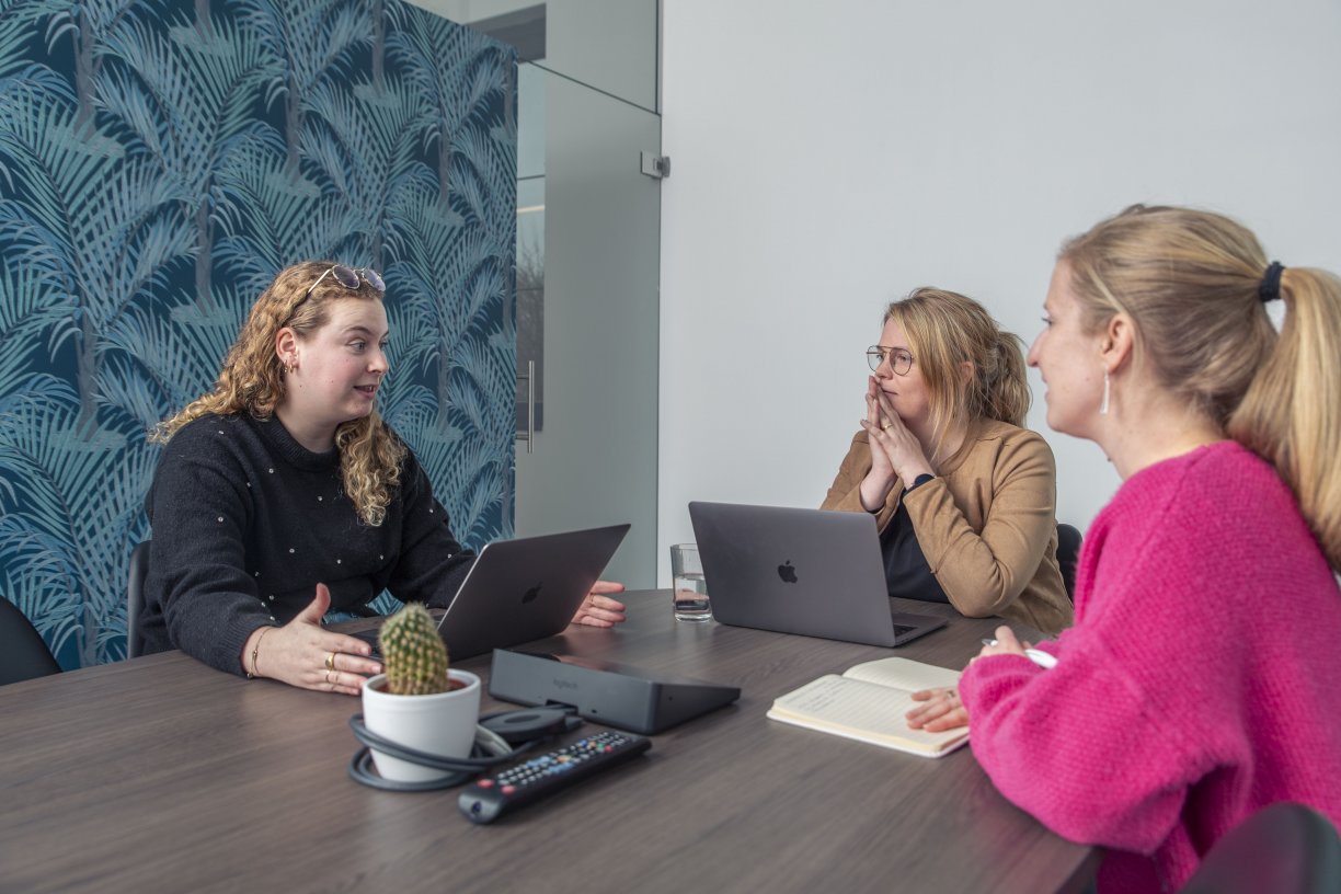 Janne, Andrea en Babette bespreken marketing strategie in de meeting room van MaesMedia in Geel.